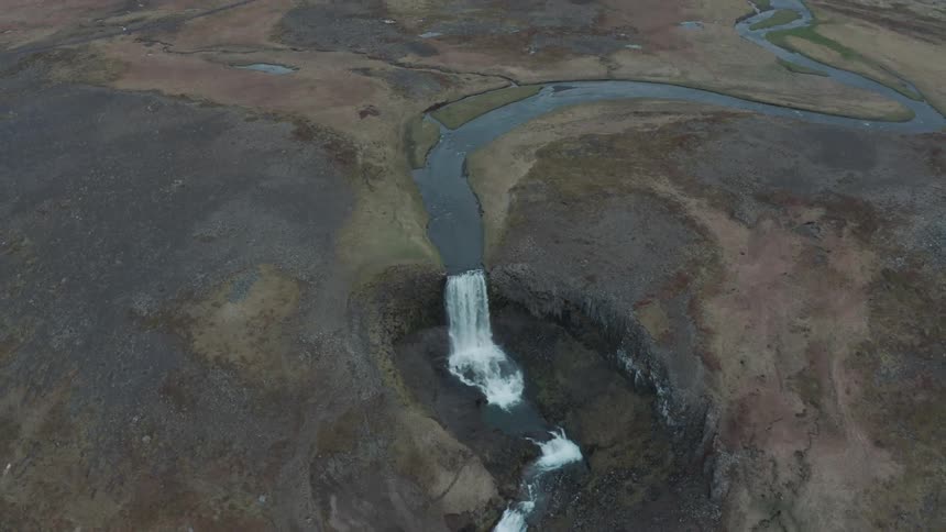 A waterfall in a natural landscape of plains and mountains