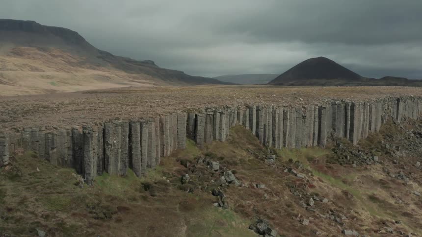 Hills rise over surrounding plateau under a dark overcast sky
