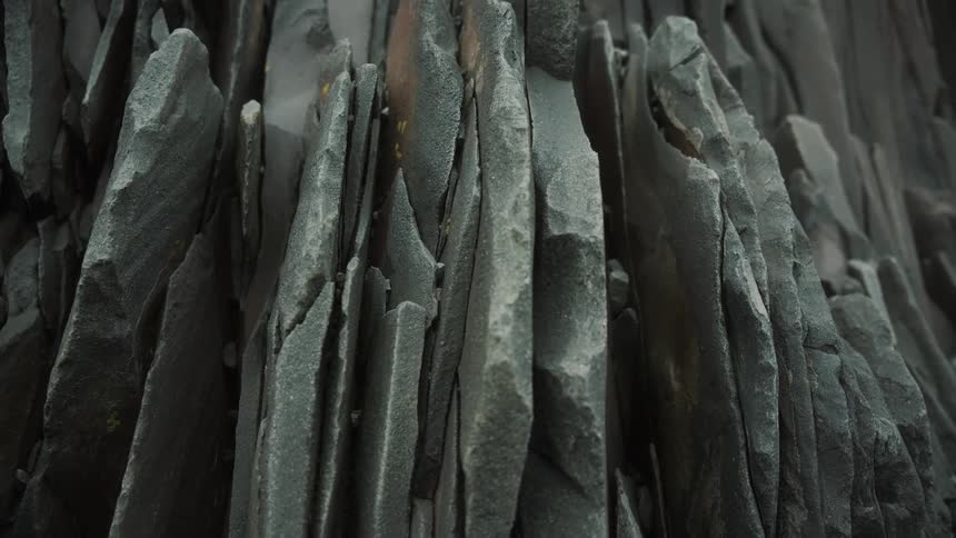 A pile of dark jagged rocks or slate pieces