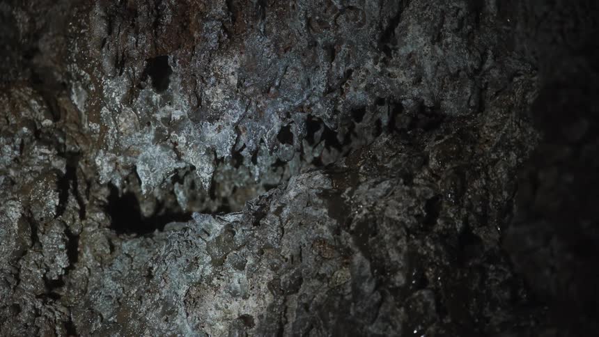 The light from a flashlight illuminates a small rocky cravice