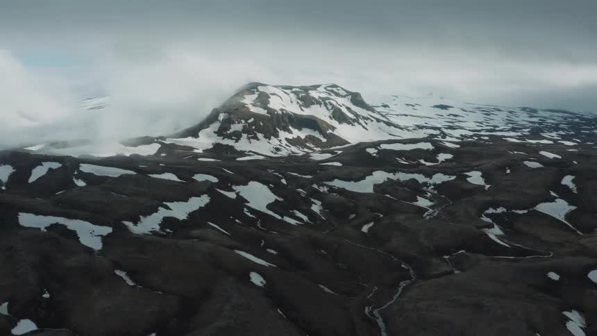 Snow covered mountain and rough terrain under a cloudy sky