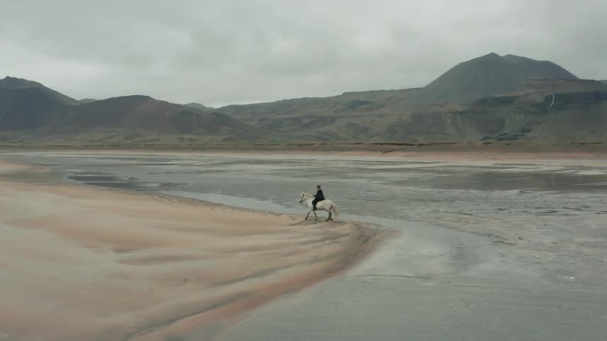 A person is riding their horse through the water