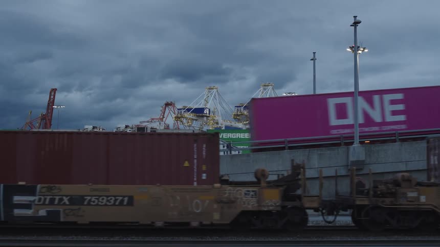 Train with containers passing in front of shipping port and container truck