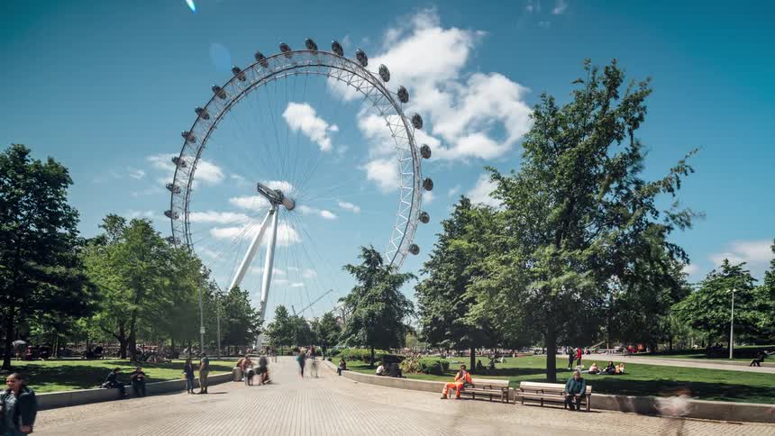 View of a square and tourist center with a ferris wheel in the background and people moving in timelapse