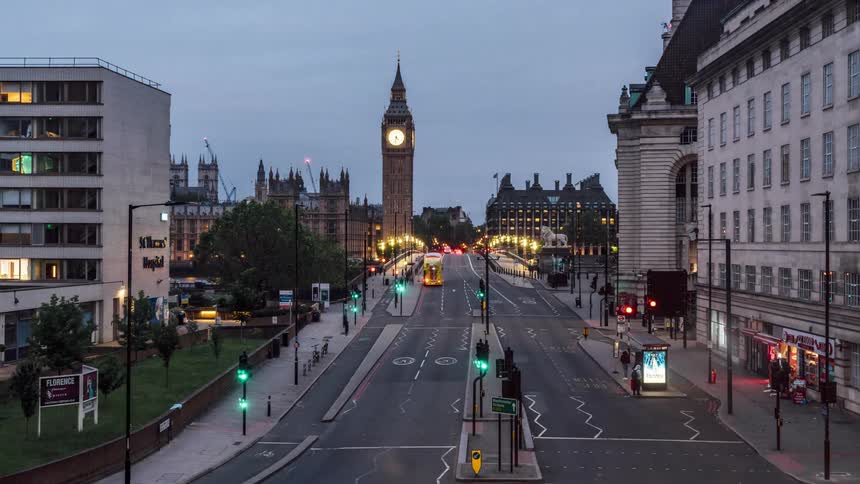 Traffic drives along road past big ben and the palace of westminster as night falls