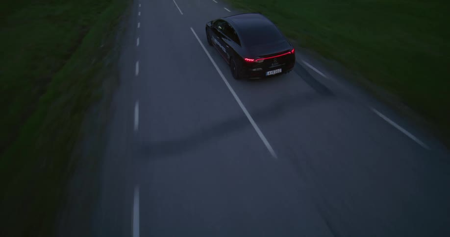 Aerial panorama of a black sports car on a road on a dark sky day