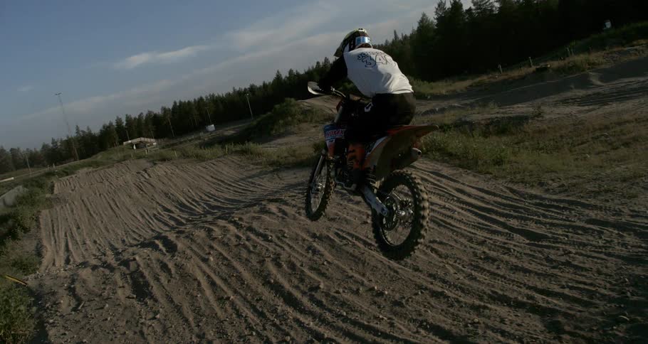 A person is jumping a dirt ramp while doing motocross