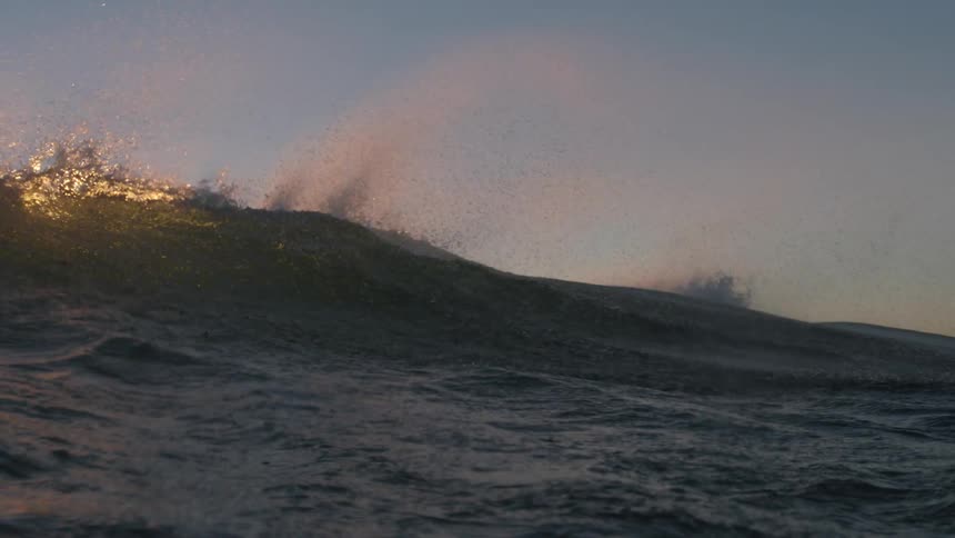 Wind blows over the ocean waves at sunset