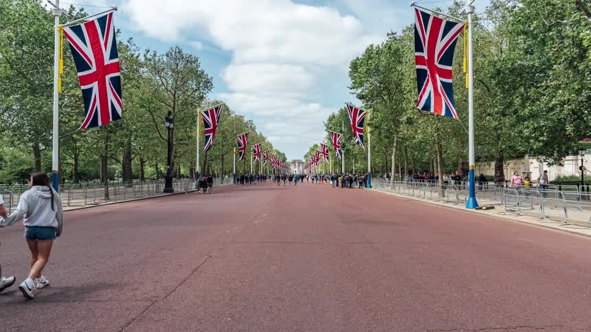 Many people walking on a path with country flags and trees on the sides