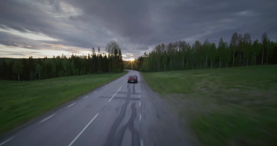 A sedan car driving really fast on a freeway on a cloudy evening