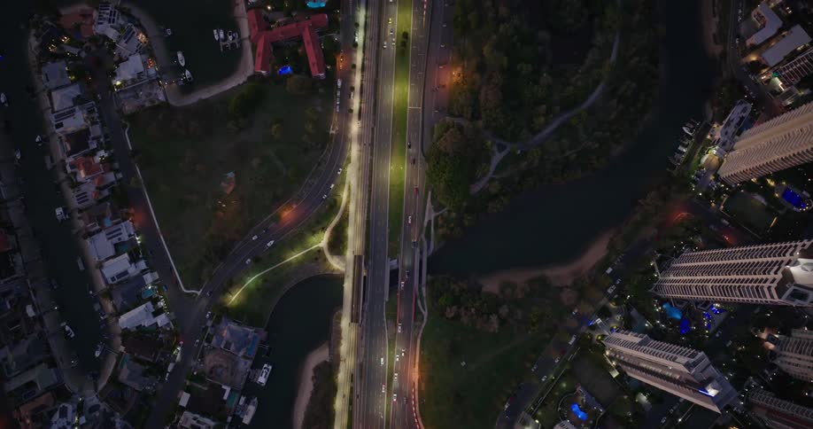 An aerial view shows a city at dusk with roads of cars and a river