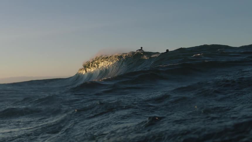 Two surfers riding a surging wave