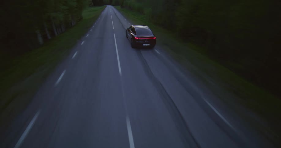 A car speeding down a road crossing a forest