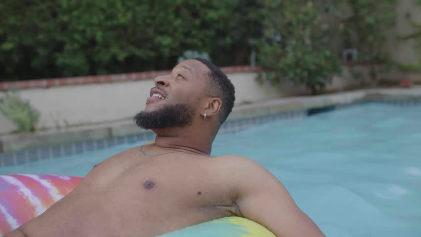Man lying on a float in the pool smiling