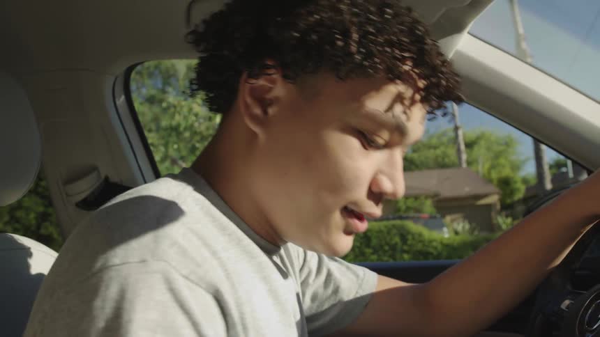 Teenager with curly hair and a gray t shirt gets in car and drives off
