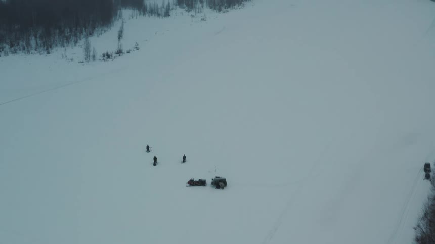 People stand in the snow by the forest