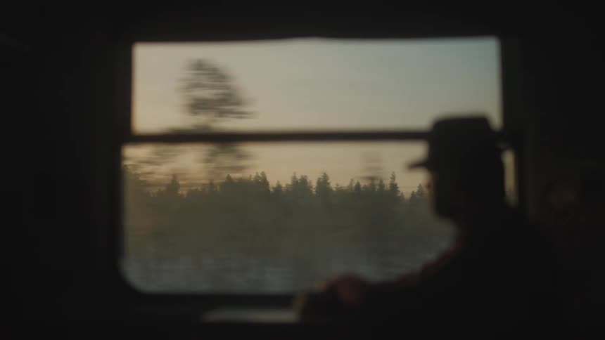 Silhouette of a man traveling by train at sunset