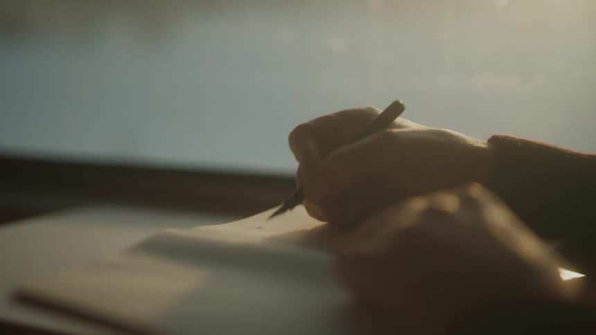 A person traveling by train writes down notes in a notebook