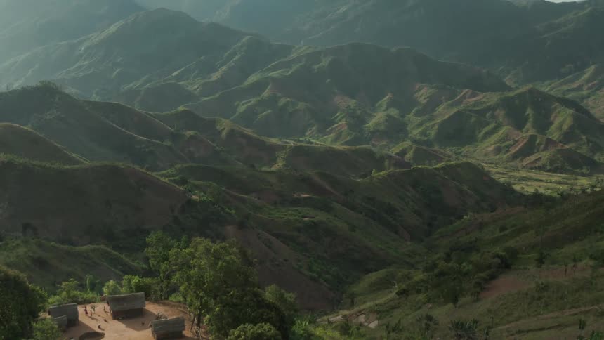Aerial view of small village over a valley surrounded with green highland hills