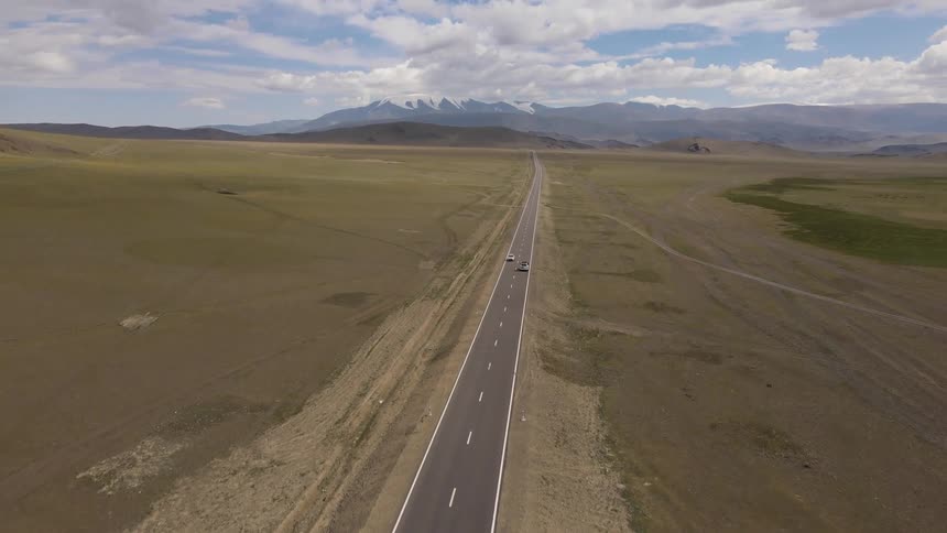 Aerial of a deserted road between plains and mountains