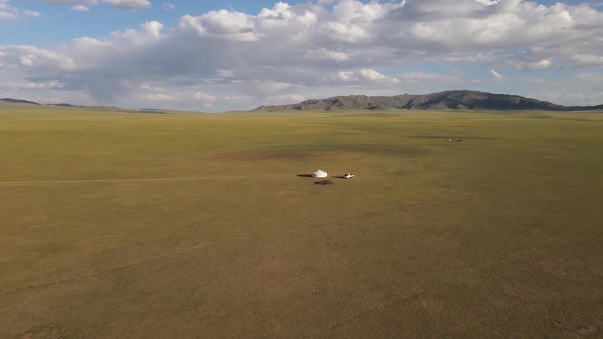 Aerial of a car and a tent in a pasture on a sunny day