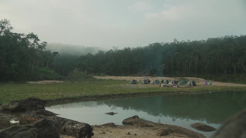 Several camping tents in front of a lake