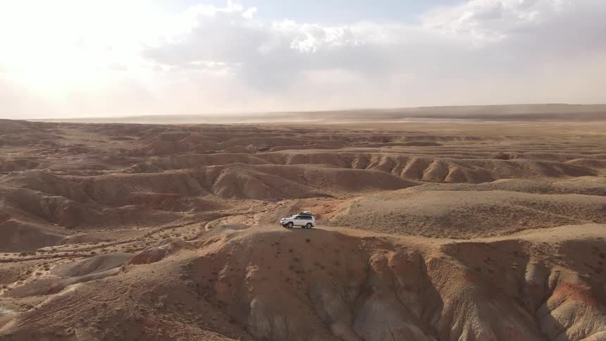 A vehicle navigating a desolate rugged landscape with erosion patterns