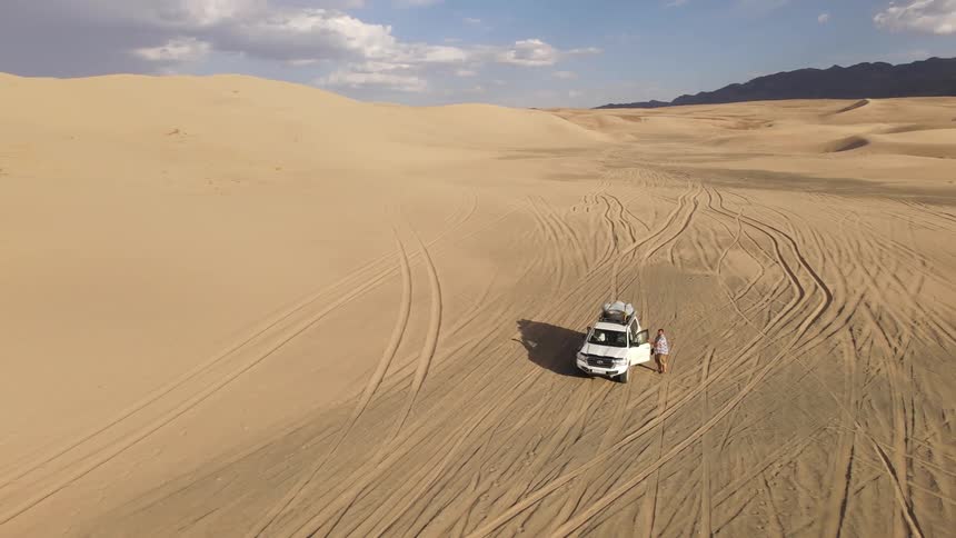 Aerial view of a white car parked in the desert
