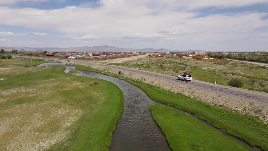Aerial of a car driving down a road in a rural town