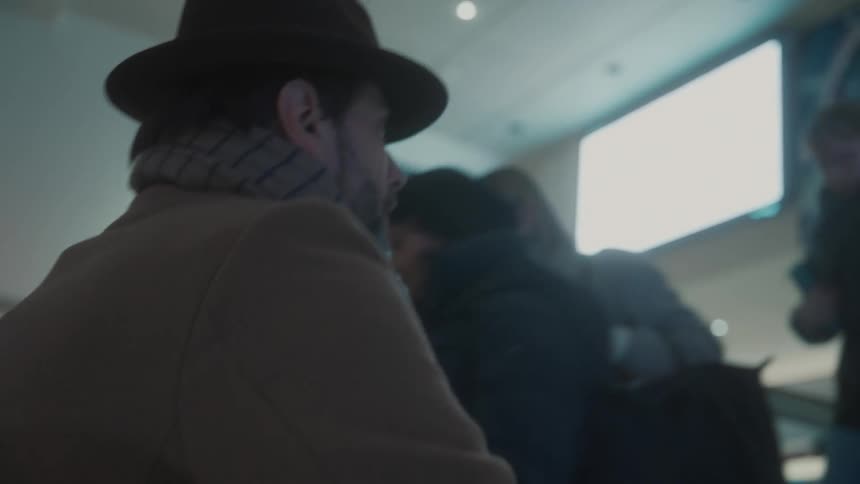 Man wearing a hat and scarf climbs the stairs of a train station