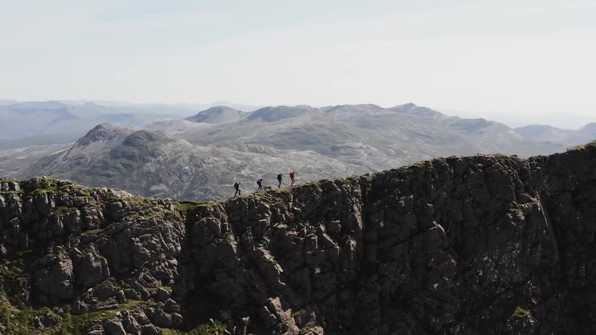 Mountaineers with a dog walk over the ridge of a mountain