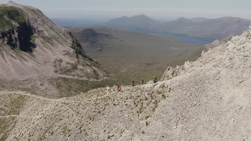 A group of people hiking across a path at the top of a mountain range
