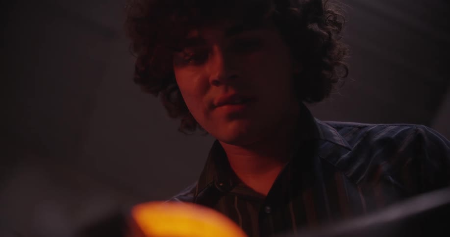 Young man welding hot iron with a hammer