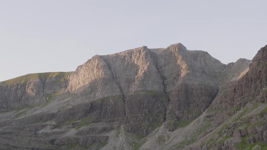 A large rock mountain with some greenery