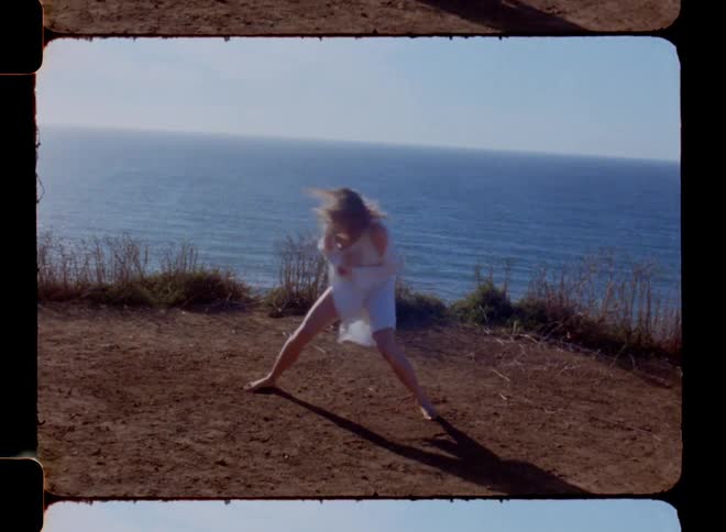 Blonde woman dancing scenically on a hill by the sea