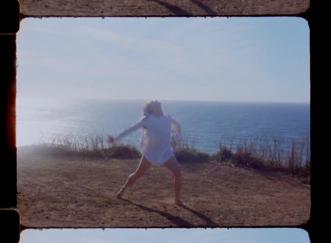 Woman dances on shore on a bright sunny day