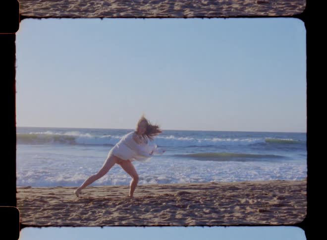 Woman on a white dress dancing in the beach at sunset