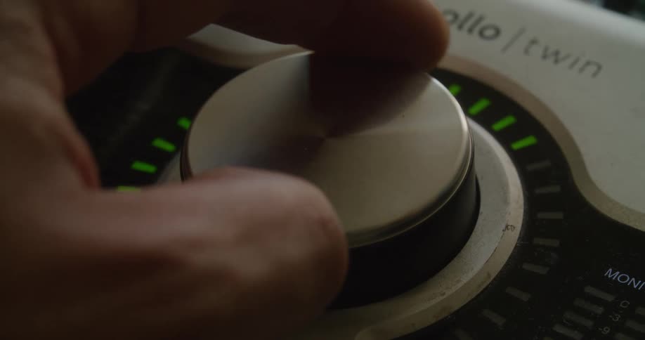 Fingers turning a large volume knob