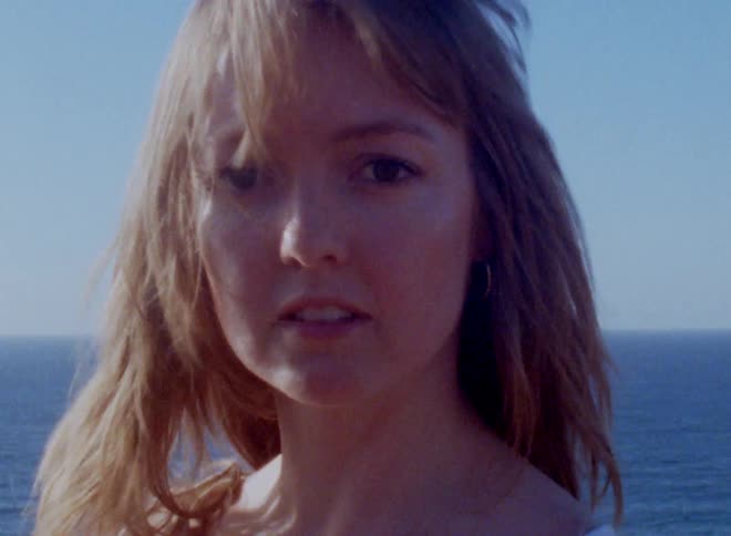 Woman with her hair blowing in the wind next to the ocean