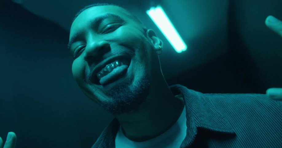 Man smiling with gold teeth in a dark room