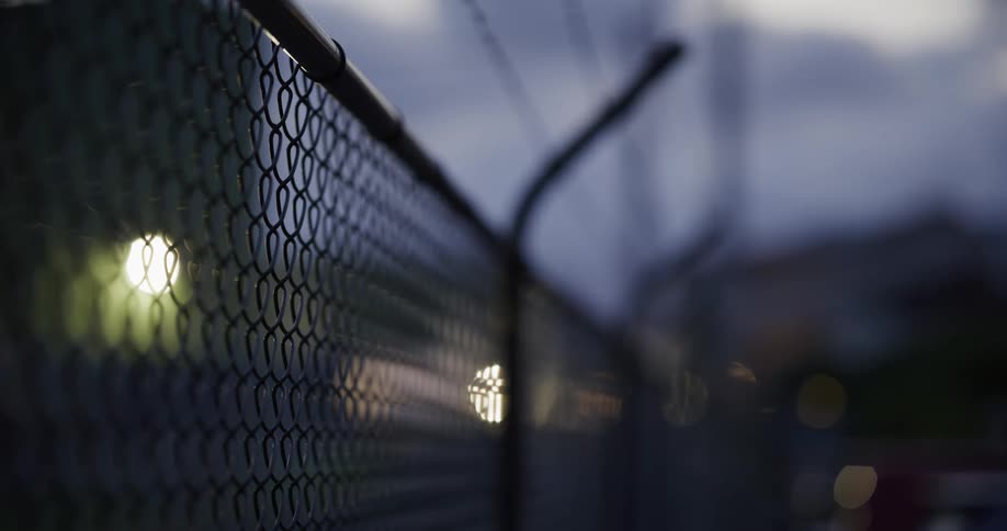 A wire fence curved at the top with barbed wire above