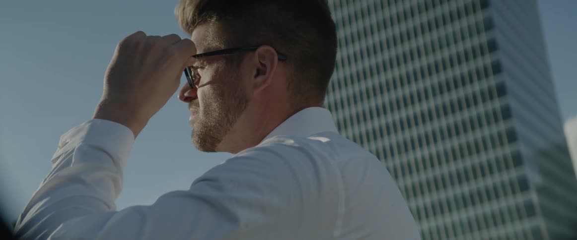 Man outside in city putting on glasses