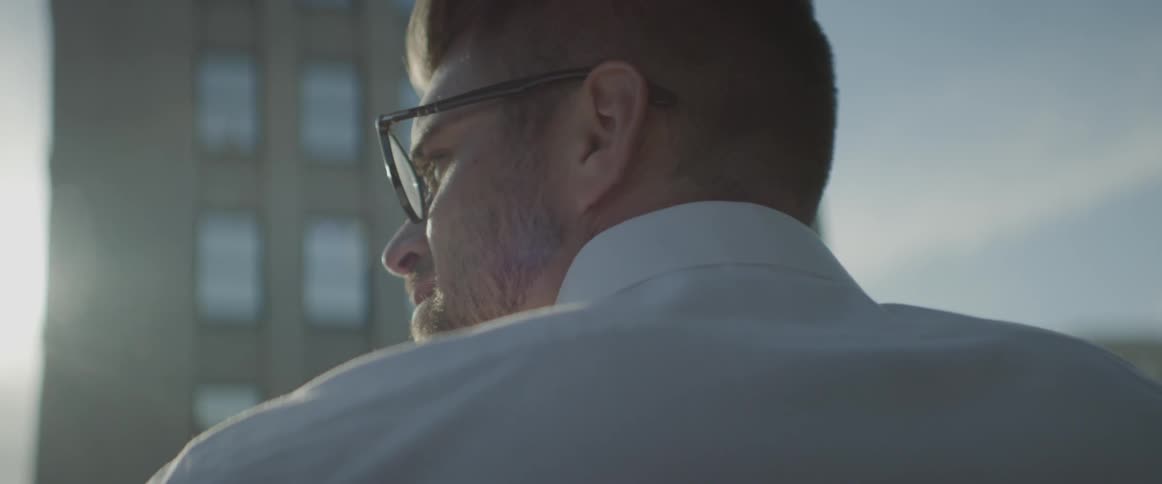 A man wearing glasses looks at buildings in a city