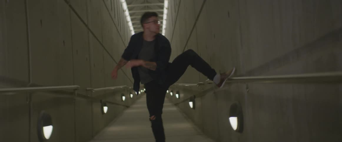 A man dances in a lighted hallway