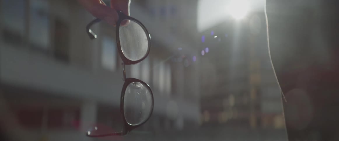 Sunlight reflecting off a pair of glasses a man is holding