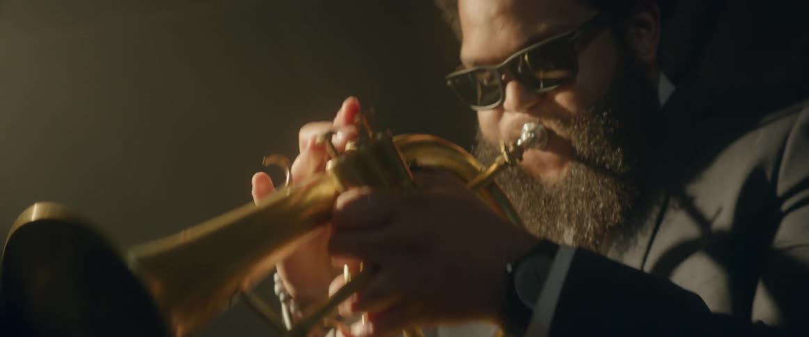 Bearded man playing his brass instrument while wearing sunglasses