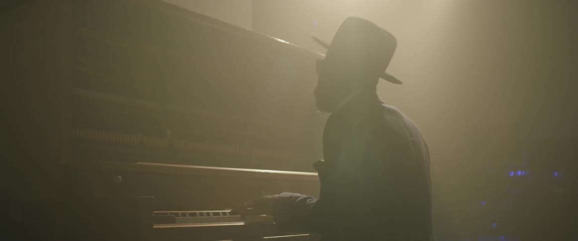 Man playing a piano as a beam of light shines upon him
