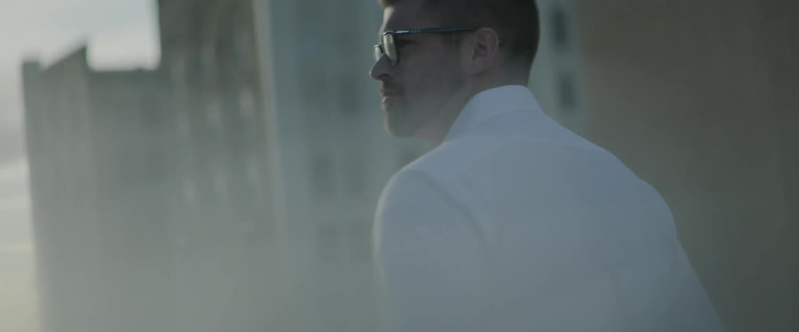 A man is walking outside by tall buildings