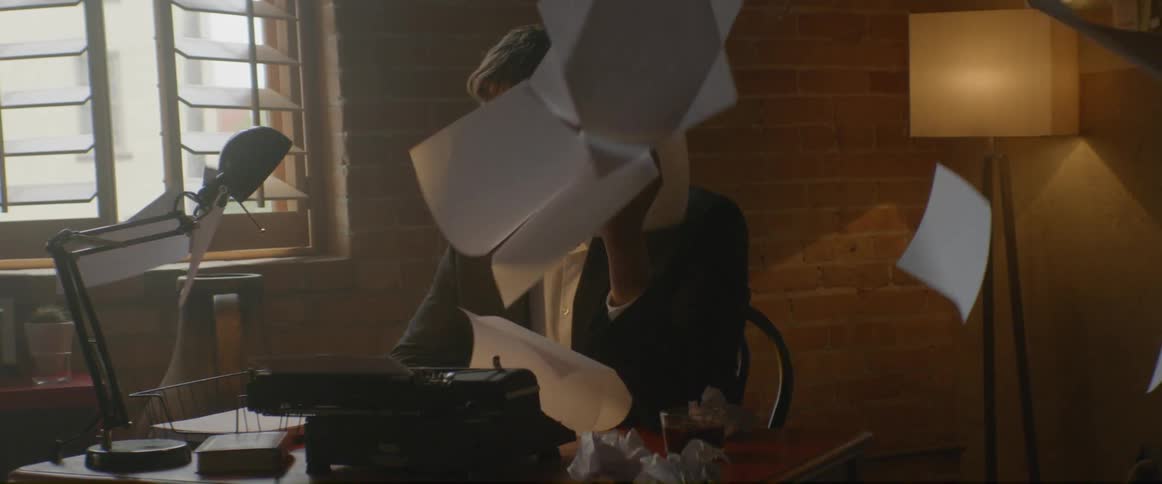Papers fall around a man seated at a desk