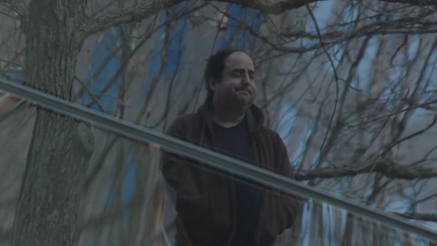 A man standing in the park as people walking by him